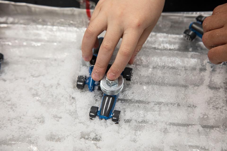 Students move different weighted cars on fake snow and ice to understand how slippery cars can be in a real-life, weather-related scenarios. 