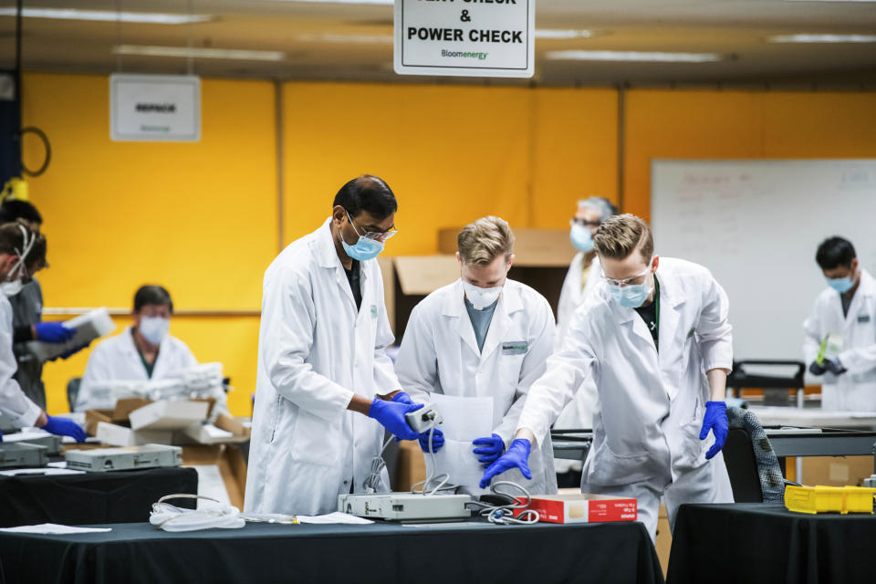 FILE - In this March 28, 2020, file photo, staff work in a ventilator refurbishing assembly line at Bloom Energy in Sunnyvale, Calif. The COVID-19 outbreak has prompted companies large and small to rethink how they do business. Bloom Energy in San Jose, Calif., makes hydrogen fuel cells. But recently, they have been refurbishing old ventilators so hospitals can use them to keep coronavirus patients alive. (Beth LaBerge/KQED via AP, Pool, File)