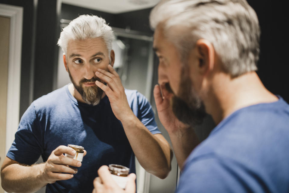 mature man putting on moisturizer