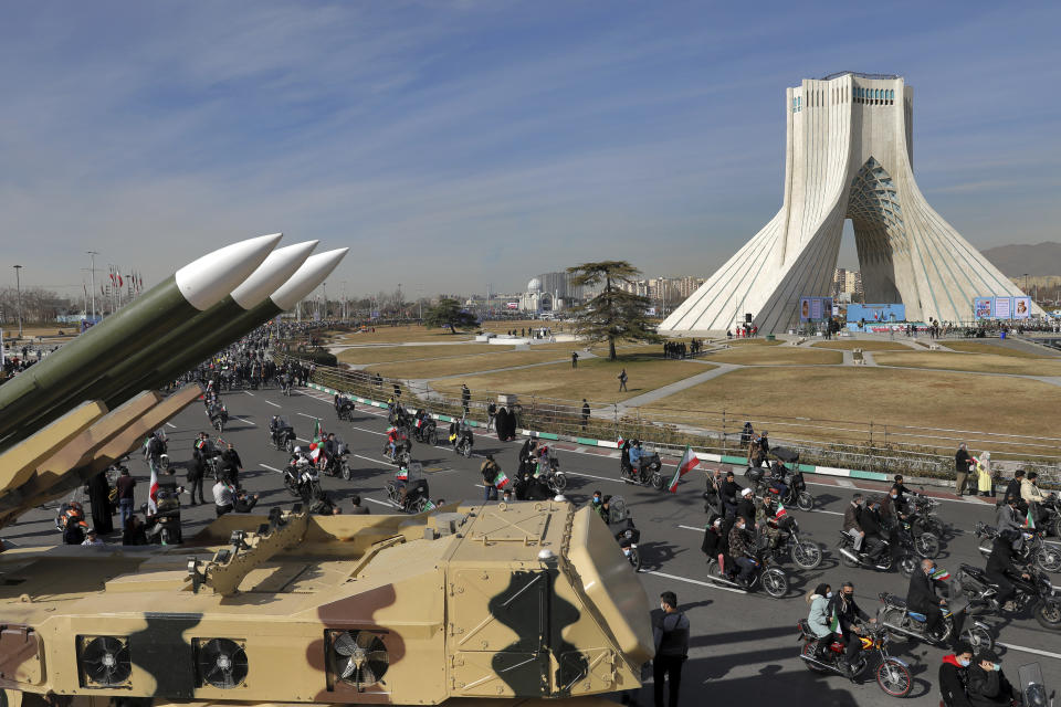 Iranians drive past missiles by their motorcycle during a rally marking the 42nd anniversary of the Islamic Revolution, at Azadi (Freedom) Square in Tehran, Iran, Wednesday, Feb. 10, 2021. Iranians Wednesday began a vehicle-only rallies in cities and towns across the country to mark the anniversary of its 1979 Islamic Revolution. The decision for replacing traditional rallies and demonstrations by vehicle-only move came as a measure to prevent spread of the coronavirus as the country struggles to stem the worst outbreak of the pandemic in the Middle East with death toll nearing 59,000 and some 1.48 million confirmed cases of the virus. The country on Tuesday launched a coronavirus inoculation campaign. (AP Photo/Ebrahim Noroozi)