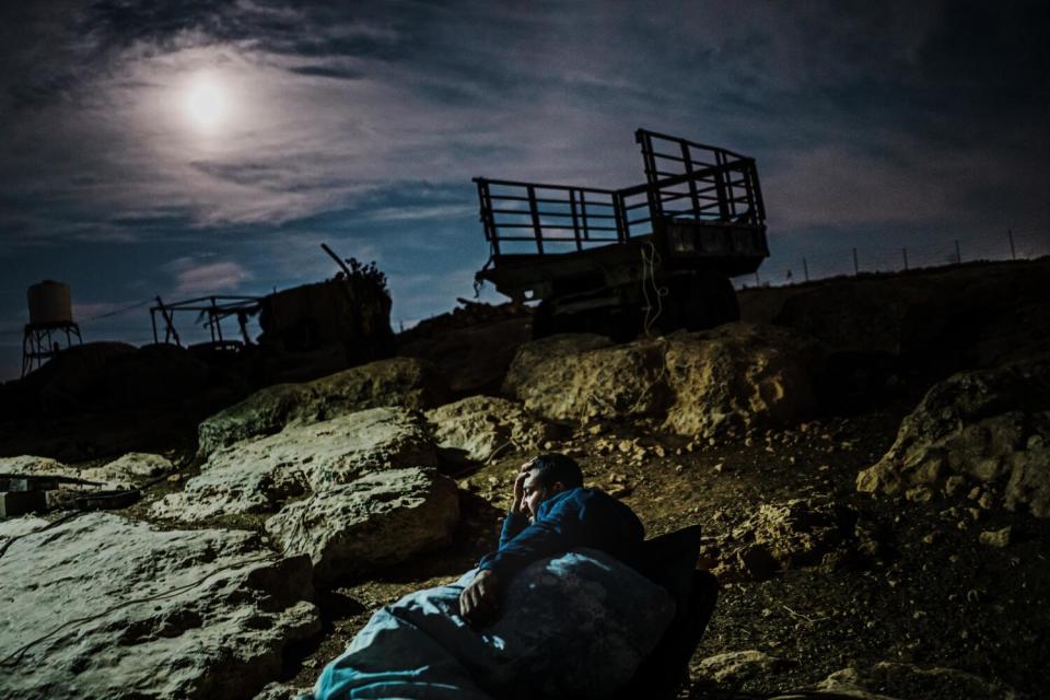 A Palestinian man sleep outside in the cold attempting to stay awake and watch out for Israeli settlers.