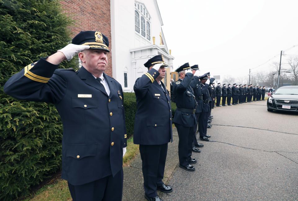 Brockton police officers salute in front of St. Ann's Church in West Bridgewater during the funeral procession for Brockton police officer Sean Besarick on Wednesday, Jan. 4, 2023.