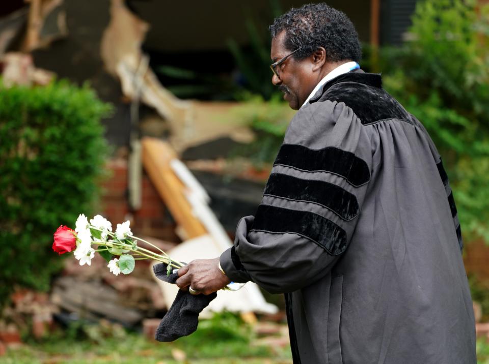 The Rev. Raymond Johnson, associate pastor of the Mt. Pisgah Baptist Church in Marion, South Carolina, carries flowers onto the front lawn of a home partially destroyed by law enforcement on April 29, 2024, during an incident in which four law enforcement officers, including three on a U.S. Marshals Task Force, were killed and four other officers were injured after being shot while attempting to serve a warrant in Charlotte, North Carolina.
