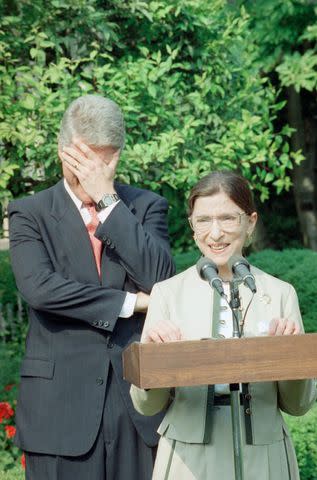 <p>AP Photo/Dennis Cook</p> President Bill Clinton covers his eyes and laughs as Ruth Bader Ginsburg speaks in the Rose Garden of the White House after her Senate confirmation in August 1993