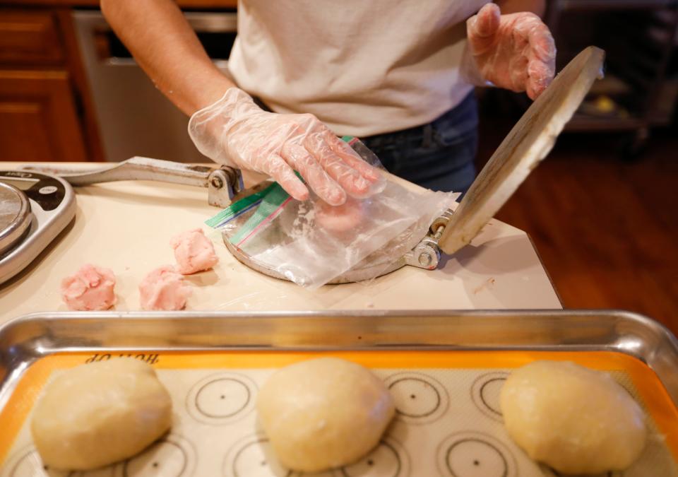 Lupita Hernandez presses dough to make the tops of conchas, a Mexican sweet bread with a topping that resembles a seashell, at her home on Wednesday, Feb. 8, 2023.