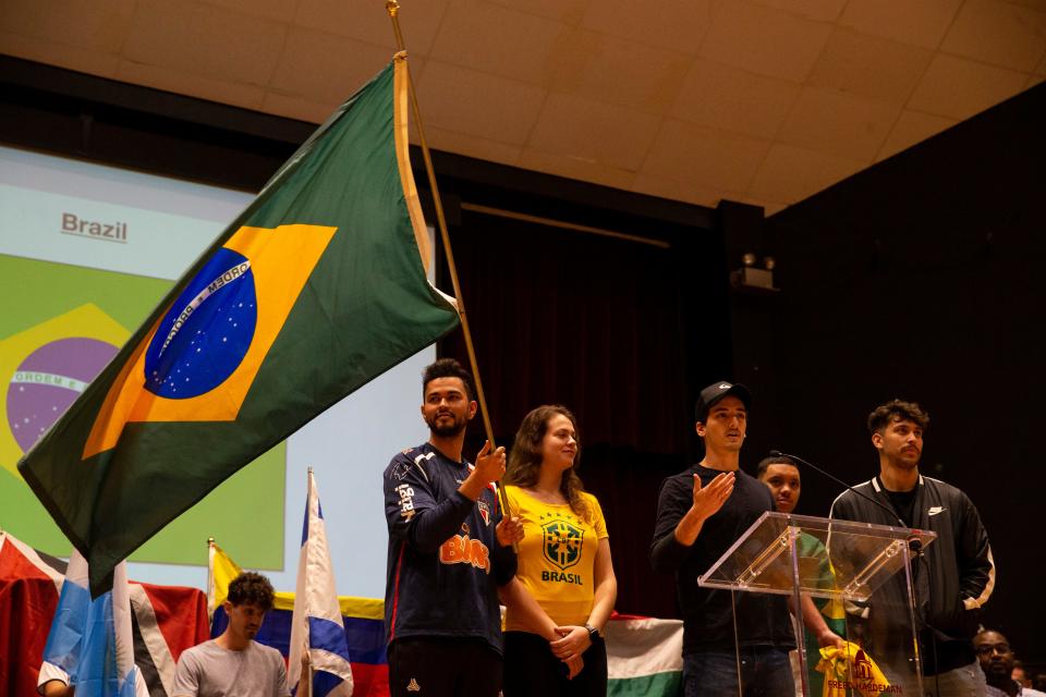 Students from Brazil speak about their country as one waves the Brazilian flag during International Student Day in Loyd Auditorium at Freed-Hardeman University in Henderson, Tenn., on Thursday, February 23, 2023. Students representing 19 countries carried their home country flags into the auditorium and then introduced their countries. 