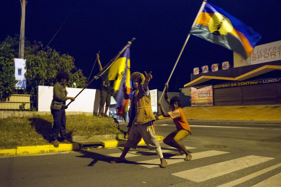 Pro-independentists strike a pose as they celebrate in the streets of Noumea, the New Caledonia's capital, while waving the indigenous Malanesian flag called the 'Kanak' flag after official results gave 43.6 percent support for independence as part of the referendum, Sunday, Nov. 4, 2018. A majority of voters in the South Pacific territory of New Caledonia chose to remain part of France instead of backing independence, election officials announced Sunday as French President Emmanuel Macron promised a full dialogue on the region's future. (AP Photo/Mathurin Derel)