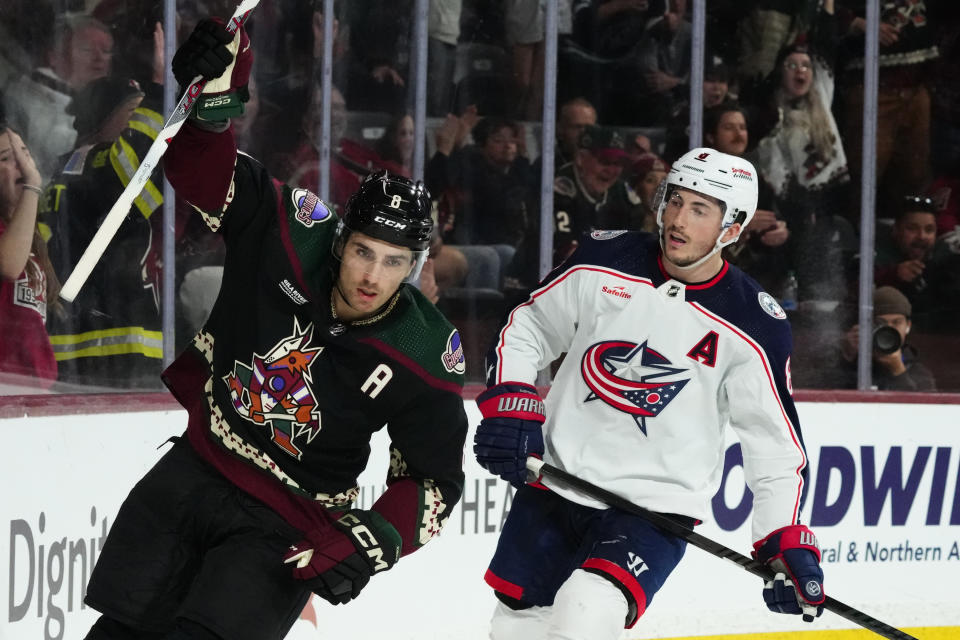 Arizona Coyotes center Nick Schmaltz (8) celebrates his shorthanded goal, next to Columbus Blue Jackets defenseman Zach Werenski during the third period of an NHL hockey game Tuesday, March 26, 2024, in Tempe, Ariz. The Coyotes won 6-2. (AP Photo/Ross D. Franklin)