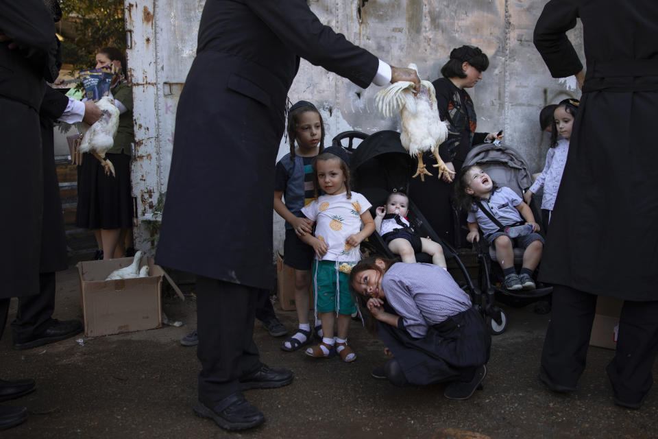 An Ultra-Orthodox Jewish man swings a chicken over his kids as part of the Kaparot ritual in Bnei Brak, Israel, Tuesday, Sept. 14, 2021. Observant Jews believe the ritual transfers one's sins from the past year into the chicken, and is performed before the Day of Atonement, Yom Kippur, the holiest day in the Jewish year which starts at sundown Wednesday. (AP Photo/Oded Balilty)