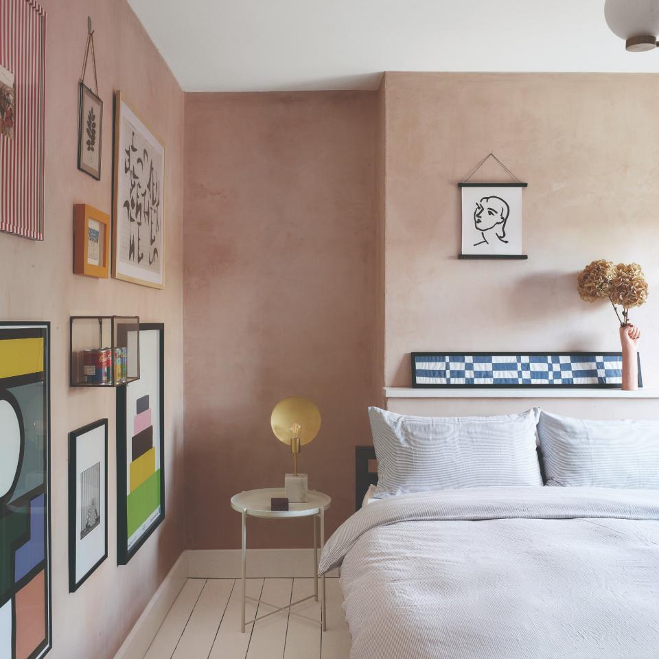 A bedroom with pink limewash walls and a gallery wall display