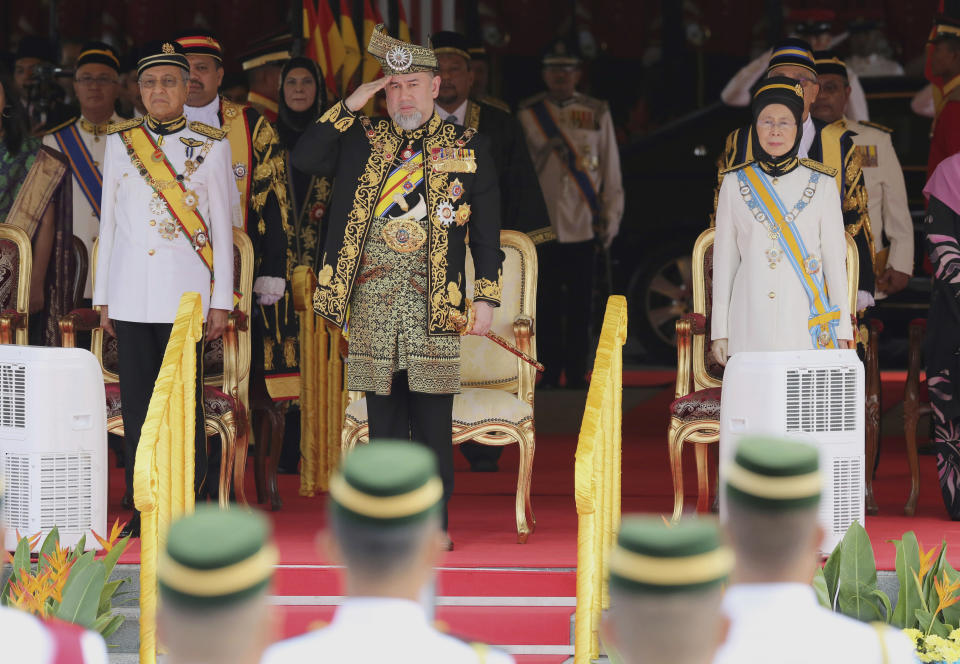 FILE - In this July 17, 2018, file photo, Malaysian King Sultan Muhammad V, center, salutes during the national anthem with Prime Minister Mahatir Mohamad, left, and Deputy Prime Minister Wan Azizah Wan Ismail, right, at the opening of the 14th parliament session at the Parliament House in Kuala Lumpur, Malaysia. Sultan Muhammad V shocked the nation by announcing his abdication in January 2019, days after returning from two months of medical leave. The 49-year-old sultan from eastern Kelantan state only reigned for two years as Malaysia's 15th king and didn't give any reason for quitting. (AP Photo/Yam G-Jun, File)