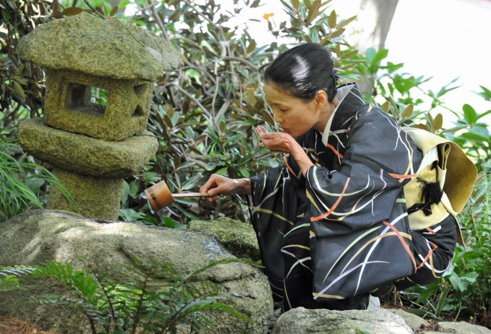 Before entering the Tea Room, "guest" Megumu Mabuchi sips water during a Japanese tea ceremony at The Art Complex Museum in Duxbury, Sunday, July 31, 2022.