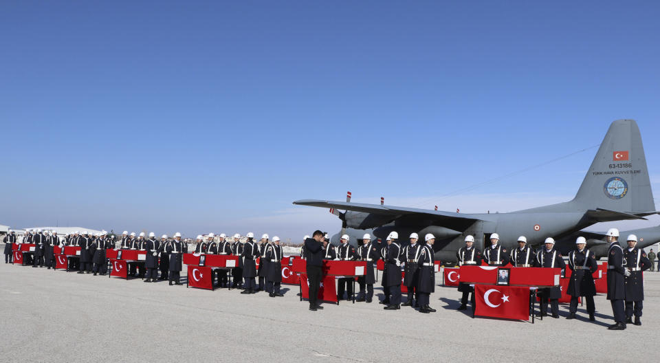Honour guards stand at the coffins of 12 soldiers who lost their lives while trying to rescue people from under snow after two deadly avalanches, in Van, Turkey, Thursday, Feb. 6, 2020. Turkish news agencies reported that search efforts have resumed in eastern Turkey, following two avalanches that killed dozens and left at least one person missing. (DHA via AP)