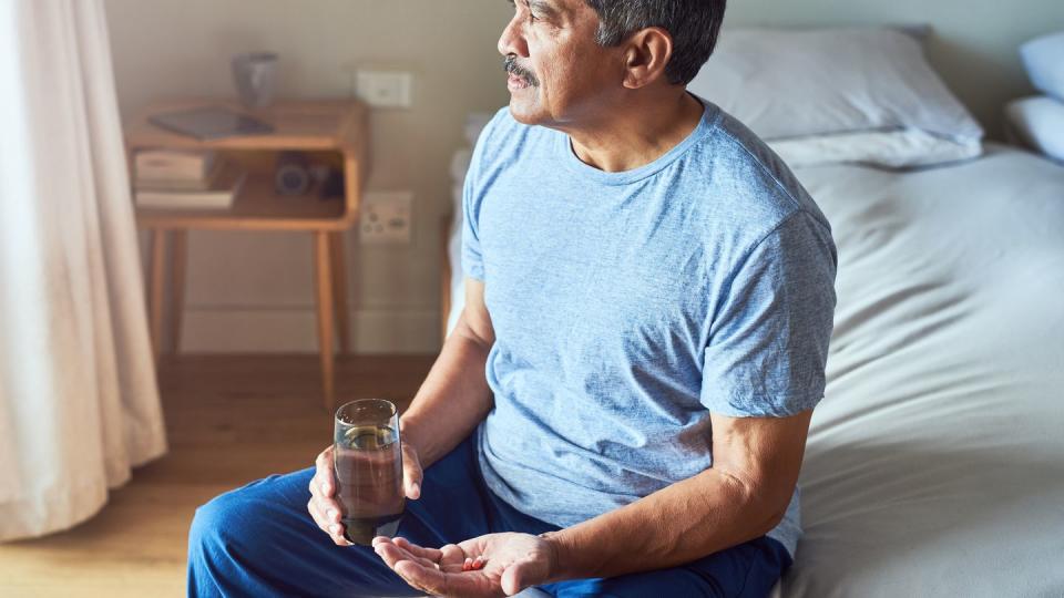 shot of a cheerful mature man seated on his bed and about to drink medication with water in the bedroom at home during the day vitamin b12 men's health