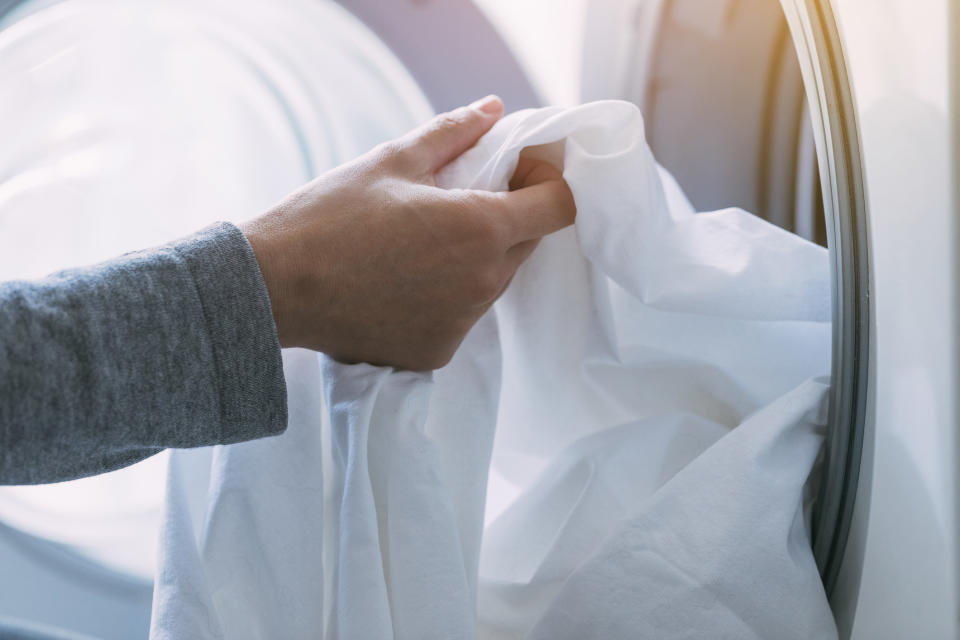 a person putting sheets in a washing machine