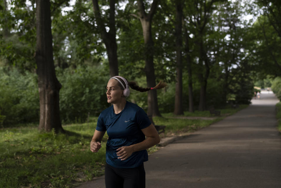 La boxeadora ucraniana Anna Lysenko trota en el jardín botánico de Kiev, Ucrania, el jueves 13 de julio de 2023. (AP Foto/Jae C. Hong)