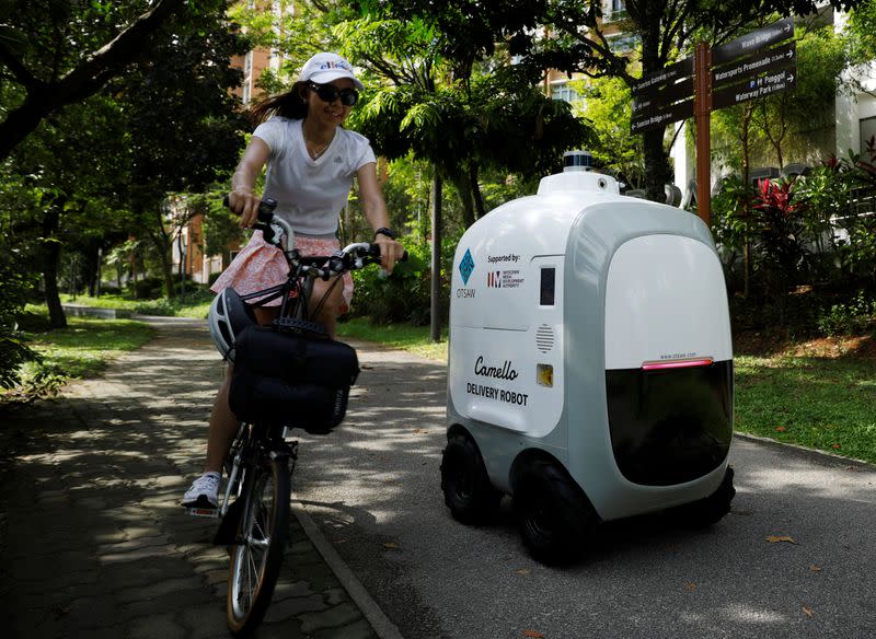 A cyclist passes as Carmello, an autonomous grocery delivery robot, makes its way during a delivery in Singapore