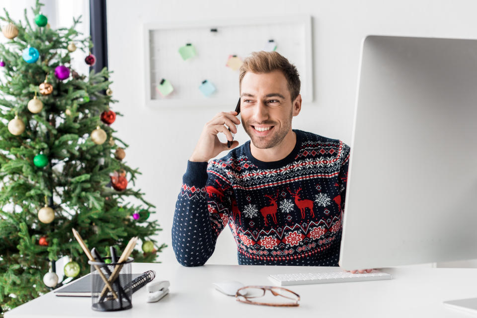 businessman in christmas sweater talking on smartphone in modern office