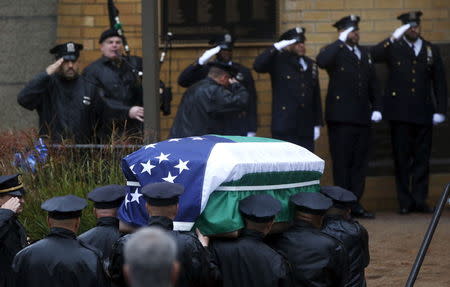 Police officers stand at attention as the casket is carried into e Greater Allen A.M.E. Cathedral of New York during the funeral service for slain New York City Police (NYPD) officer Randolph Holder in the Queens borough of New York City, October 28, 2015. REUTERS/Brendan McDermid