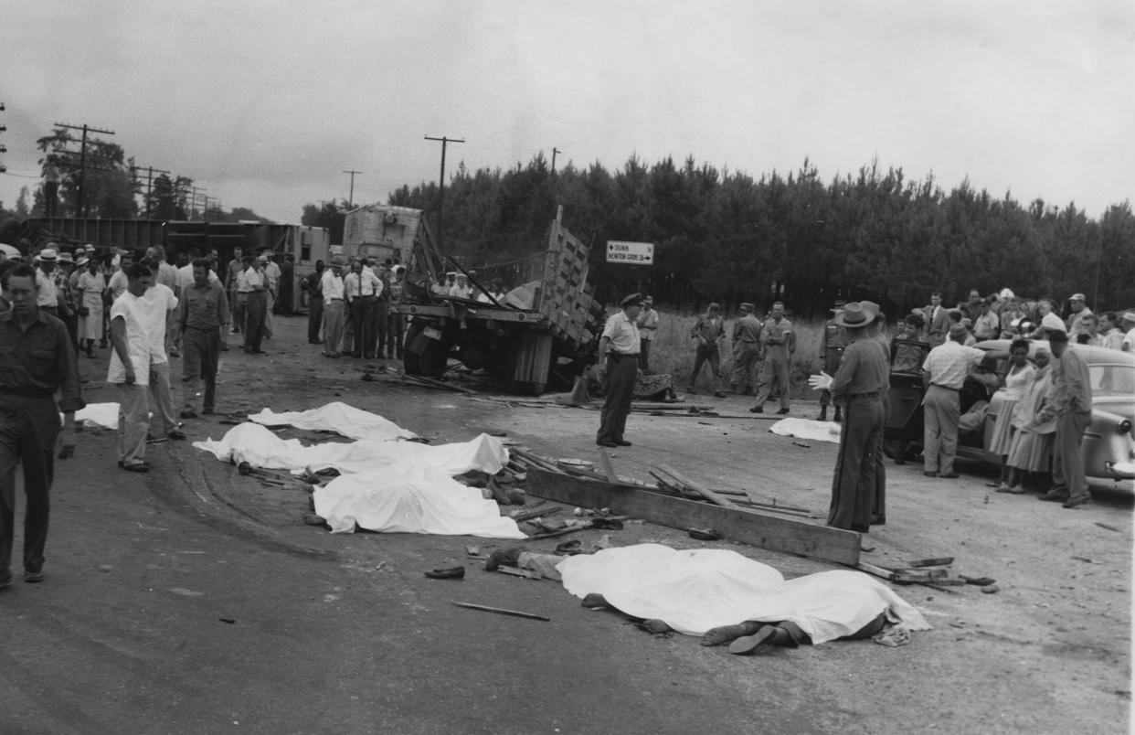 Bodies covered by sheets cover U.S. 301 near the wrecked remains of a farm truck. Twenty-one people died in this June 6, 1957, wreck in Eastover. It was the deadliest wreck in state history. [N.C. Highway Patrol]