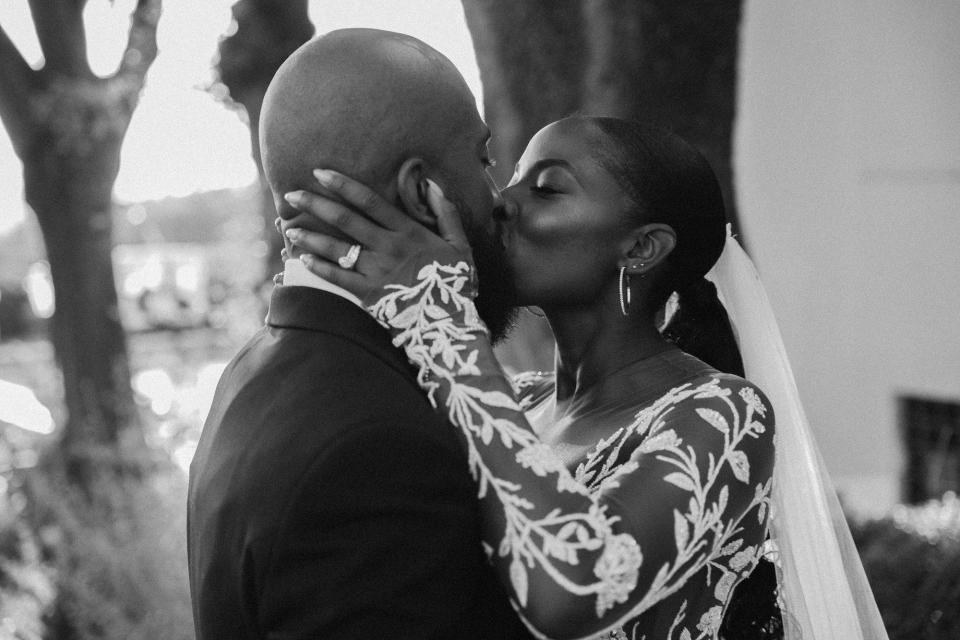 A black-and-white photo of a bride and groom kissing.