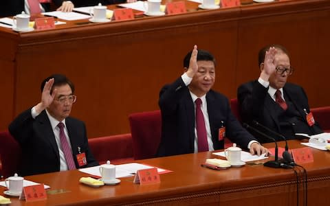 Chinese President Xi Jinping (C) raises his hand to vote for the reports with China's former presidents Jiang Zemin (R) and Hu Jintao (L) at the closing of the 19th Communist Party Congress - Credit: GREG BAKER/AFP/Getty Images