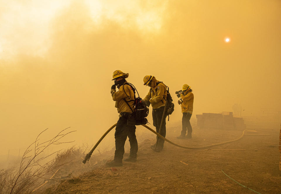 Firefighters with Cal Fire are enveloped in smoke as fire from the Green Fire passes by near homes on Hidden Glen Lane and Hidden Hills Road in Yorba Linda, Calif., Monday, Oct. 26, 2020. (Leonard Ortiz/The Orange County Register via AP)