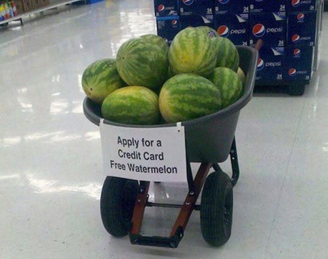 sign reading apply for a credit card free watermelon on a barrel of watermelons