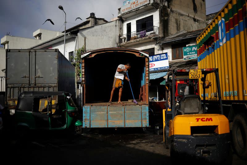 A laborer cleans a truck after unloading the sacks of rice at a wholesale market, amid the country's economic crisis in Colombo