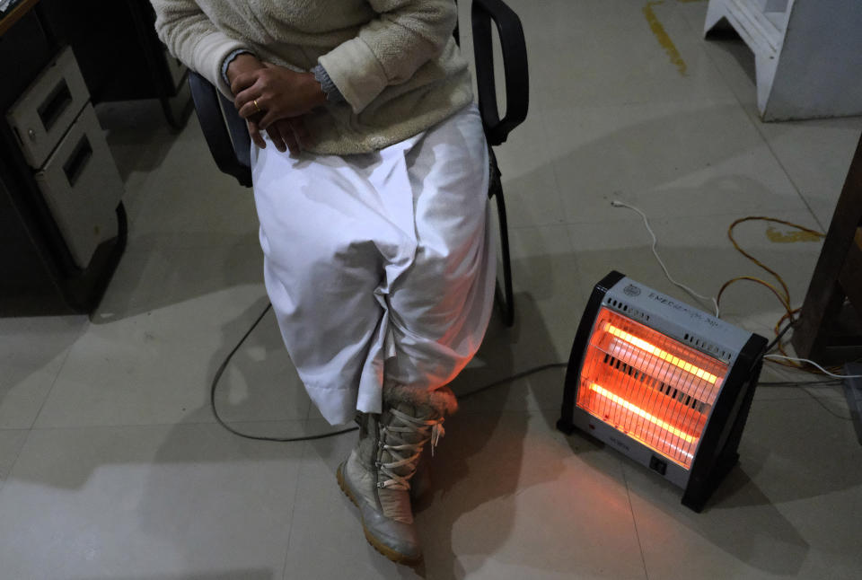 Nurse Shimray Wungreichon, 43, sits by a heater as the only nurse on overnight duty at the emergency ward of District Hospital in Ukhrul, in the northeastern Indian state of Manipur, Friday, Jan. 15, 2021. Wungreichon, who was among the first of many Indian health workers to be vaccinated on Saturday, rues about the lack of facilities in the government hospital that caters to a population of around 180,000 people, mostly indigenous Tangkhul Nagas. (AP Photo/Yirmiyan Arthur)