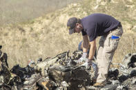 In this image taken Monday, Jan. 27, 2020, and provided by the National Transportation Safety Board, NTSB investigators Adam Huray, foreground, and Carol Hogan examine wreckage as part of the NTSB’s investigation of a helicopter crash near Calabasas, Calif. The Sunday, Jan. 26 crash killed former NBA basketball player Kobe Bryant, his 13-year-old daughter, Gianna, and seven others (James Anderson/National Transportation Safety Board via AP)