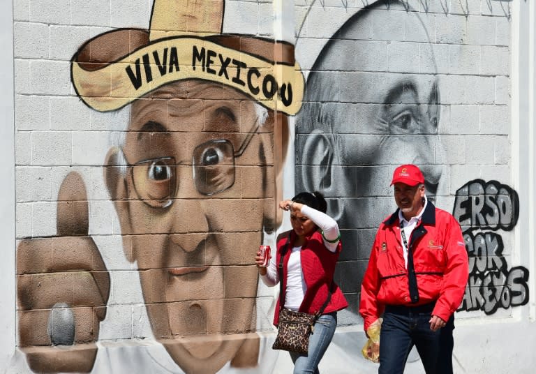 A couple walk past a mural welcoming Pope Francis to Ecatepec, on the north east side of Mexico City, February 5, 2016