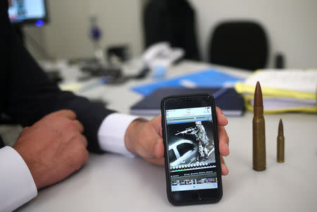 A police chief from the Bank Stealing Investigations Department holds a phone showing images and a security camera, in which a thief uses a rifle, a helmet and a bulletproof vest during a bank robbery, in Sao Paulo, Brazil February 8, 2019. REUTERS/Amanda Perobelli