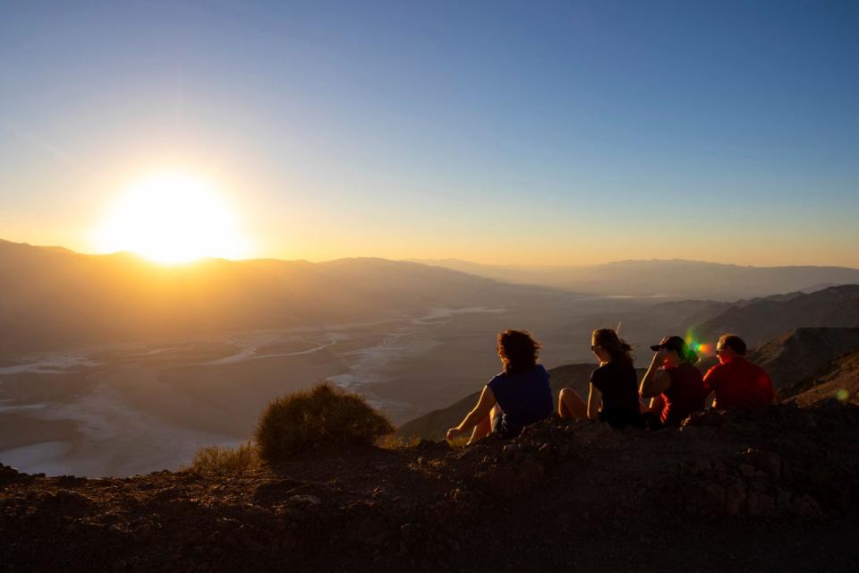 Park visitors watch the sunset on Tuesday 11 July 2023 in Death Valley National Park (AP)