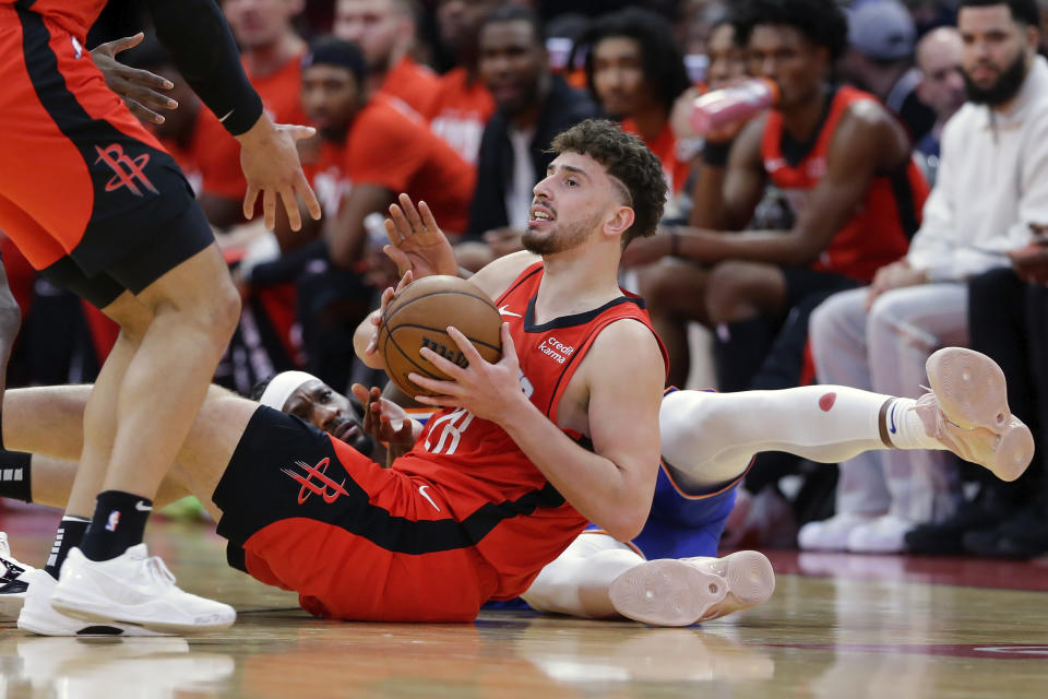 Houston Rockets center Alperen Sengun, front right, looks to pass the ball after a floor scramble with New York Knicks forward Precious Achiuwa, bottom left,, during the first half of an NBA basketball game Monday, Feb. 12, 2024, in Houston. (AP Photo/Michael Wyke)