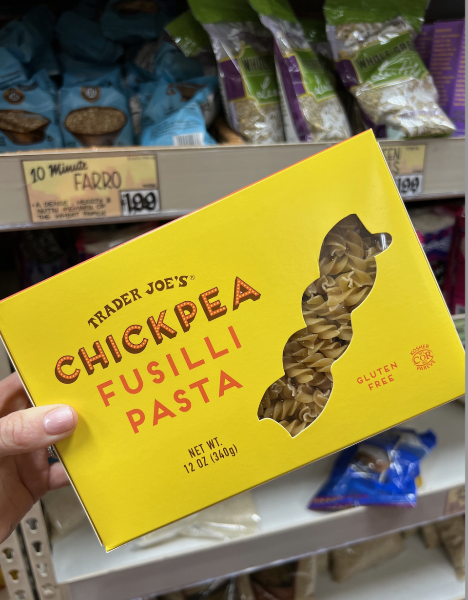 A hand holds a box of Trader Joe's Chickpea Fusilli Pasta.