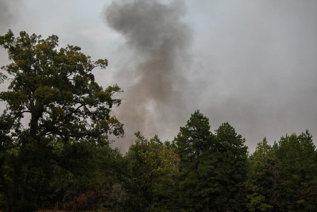 Heavy smoke from a large wildfire is seen rising from behind trees on September 2, 2023, near Huntsville in Walker County, Texas.