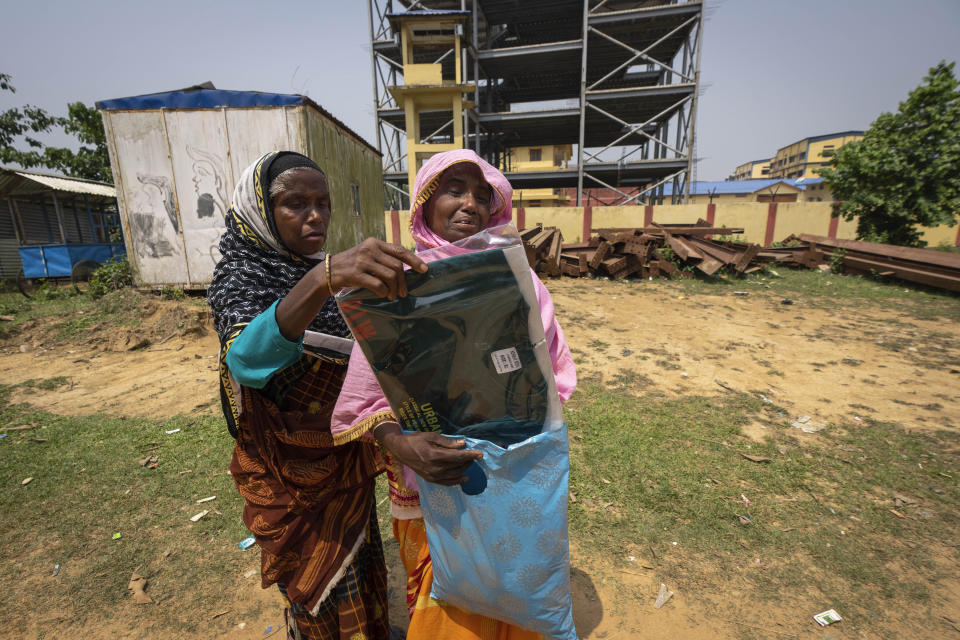 Asiya Khatoon, right, carrying a T-shirt, trousers and a cap that she wants to give her husband Abul Kalam, cries as she walks towards a detention center in Matiya village, northeastern Assam state, India, April 17, 2023. Khatoon had travelled nearly 31 kilometers (19 miles) from her home to the detention center where her husband has been held since January. They (police) just came and picked up my husband saying he is a Bangladeshi,” the 45-year-old said before hurriedly walking toward the center. (AP Photo/Anupam Nath)