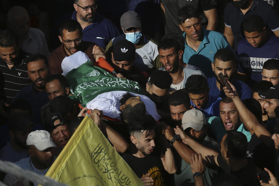 Mourners chant Islamic slogans while carrying the body of Mohammed Abu Ammar during his funeral along the streets of Bureij refugee camp, central Gaza Strip, Thursday, Sept. 30, 2021. Israeli troops shot and killed Abu Ammar, a 40-year-old Palestinian man, on Thursday as he was setting bird traps in the Gaza Strip near the Israeli border, his family said. The military said it was investigating. (AP Photo/Adel Hana)