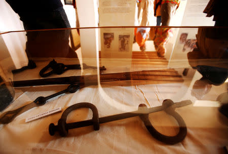 FILE PHOTO: Visitors are reflected in a glass display case containing iron leg shackles at the House of Slaves museum on Goree Island near Senegal's capital Dakar, March 16, 2007. REUTERS/Finbarr O'Reilly