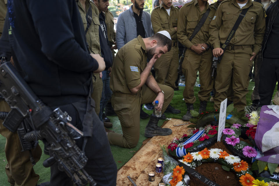 Friends of Israeli soldier Lt. Yaacov Elian mourn over his grave during his funeral at Kiryat Shaul cemetery in Tel Aviv, Israel, Friday, Dec. 22, 2023. Elian, 20, was killed during Israel's ground operation in the Gaza Strip, where it has been battling Palestinian militants in the war ignited by Hamas' Oct. 7 attack into Israel. (AP Photo/Oded Balilty)