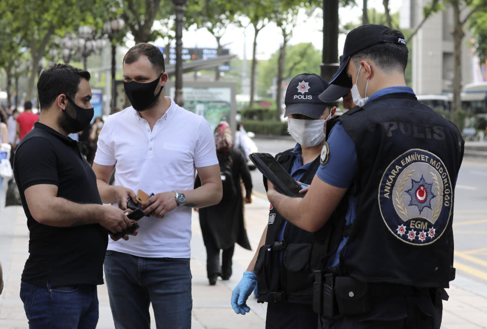 Police officers check people's IDs in the city center, in Ankara, Turkey, Thursday, June 18, 2020. Turkish authorities have made the wearing of masks mandatory in three major cities to curb the spread of COVID-19 following an uptick in confirmed cases since the reopening of many businesses.(AP Photo/Burhan Ozbilici)