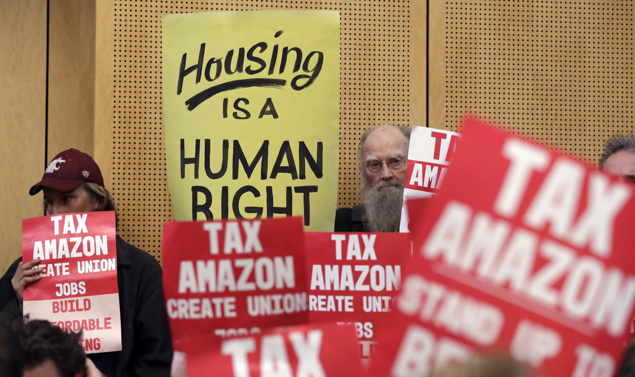 FILE - In this May 14, 2018 file photo, members of the public look on at a Seattle City Council before the council voted to approve a tax on large businesses such as Amazon and Starbucks to fight homelessness in Seattle. Seattle city leaders say Monday, June 11, 2018, they'll work to repeal a tax passed just last month on businesses such as Amazon and Starbucks designed to help pay for homeless services and affordable housing. Amazon and other businesses had sharply criticized the levy and the online retail giant even temporarily halted construction planning on a new high-rise building near its Seattle headquarters in protest. (AP Photo/Elaine Thompson, File)