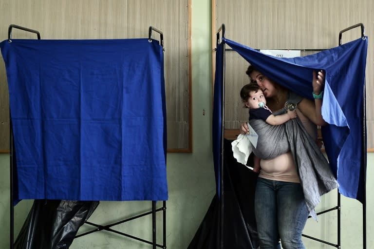 A woman and her baby leave a polling booth at a polling station in central Athens on September 20, 2015