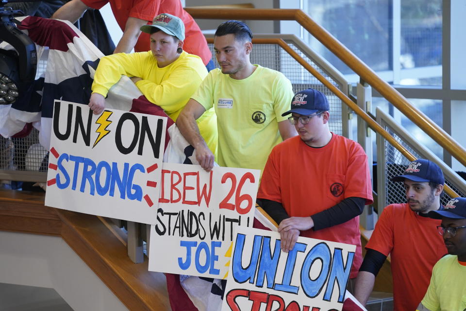 Union members hold signs before President Joe Biden speaks about the economy to union members at the IBEW Local Union 26, Wednesday, Feb. 15, 2023, in Lanham, Md. (AP Photo/Evan Vucci)