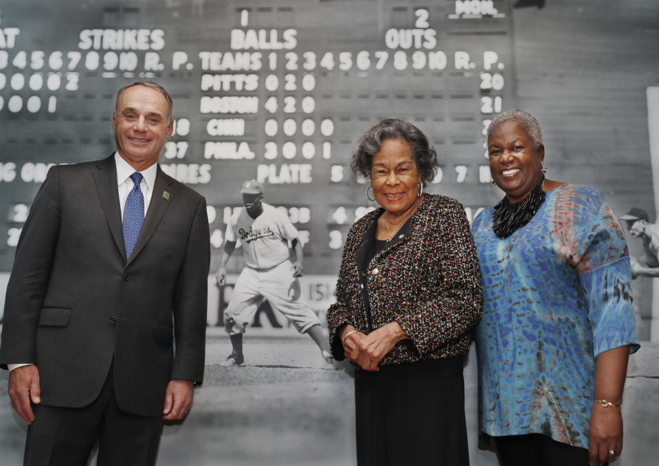 Major League Baseball Commissioner Rob Manfred, left, Rachel Robinson, center, widow of the late Jackie Robinson, and Sharon Robinson, the couple's daughter, pose in front of a mural-sized photograph of Jackie Robinson in uniform displayed at the Museum of the City of New York, Thursday, Jan. 31, 2019, in New York. The photo is part of "In the Dugout with Jackie Robinson," an exhibition celebrating Robinson's 100th birthday, mounted in collaboration with The Jackie Robinson Foundation. The exhibit features 30 photographs originally shot for Look Magazine (most never published) and rare Robinson family home movies plus memorabilia related to Robinson's career. (AP Photo/Kathy Willens)