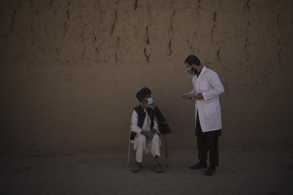 Dr. Obaidullah Ayoubi, right, checks an elderly patient in Utari village, Wardak province, Afghanistan, Tuesday, Oct. 12, 2021. In urban centers, public discontent toward the Taliban is focused on threats to personal freedoms, including the rights of women. In Salar, these barely resonate. The ideological gap between the Taliban leadership and the rural conservative community is not wide. Many villagers supported the insurgency and celebrated the Aug. 15 fall of Kabul which consolidated Taliban control across the country. (AP Photo/Felipe Dana)