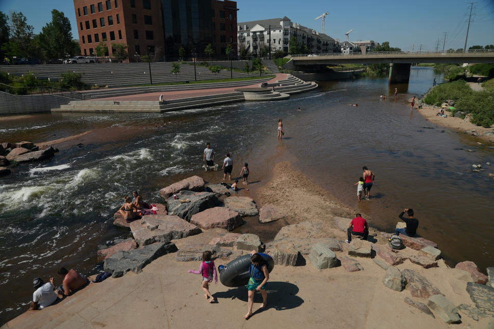 People cool off in the water at the confluence of the South Platte River and Cherry Creek in Denver, Colorado on June 14, 2021. By mid-afternoon, the temperature hit 96 degrees as part of the heat wave sweeping across the western U.S. (AP Photo/Brittany Peterson)