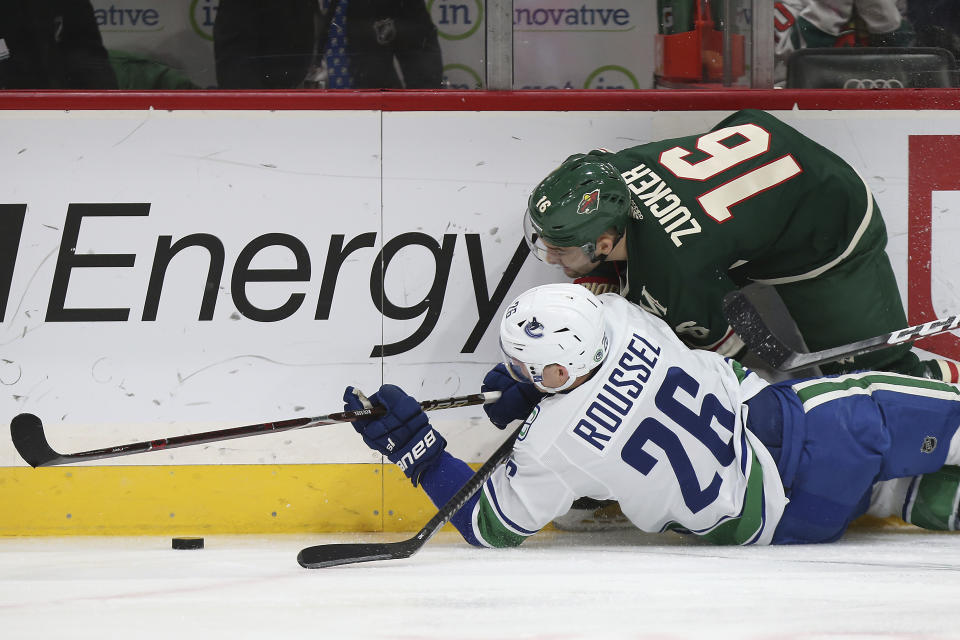 Minnesota Wild's Jason Zucker (16) and Vancouver Canucks' Antoine Roussel, of France, fight for the puck in the second period of an NHL hockey game Sunday, Jan. 12, 2020, in St. Paul, Minn. (AP Photo/Stacy Bengs)