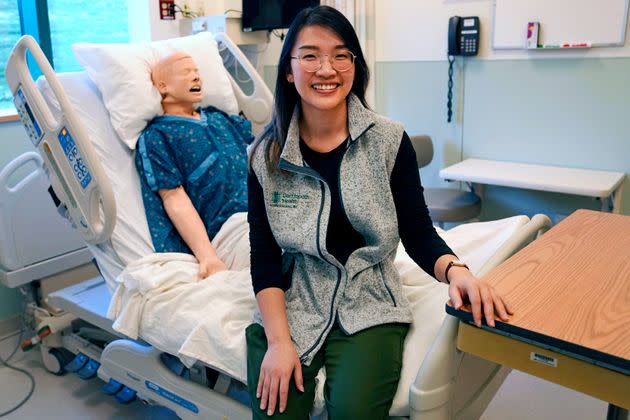 Andy Hoang, a recent nursing graduate who suffered cardiac arrest, poses with a training mannequin in a patient bedroom training lab at Dartmouth-Hitchcock Medical Center. 
